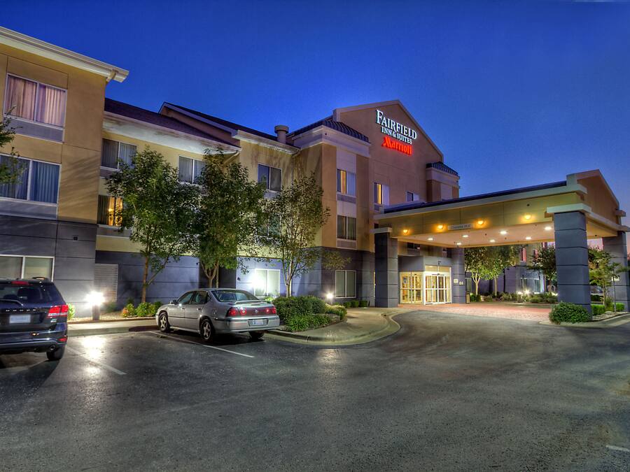 A Fairfield Inn & Suites by Marriott hotel with a parking lot and two cars parked in front.