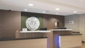 Un área de recepción con dos mostradores de madera, un adorno de pared y un cartel sobre el mostrador de la derecha.