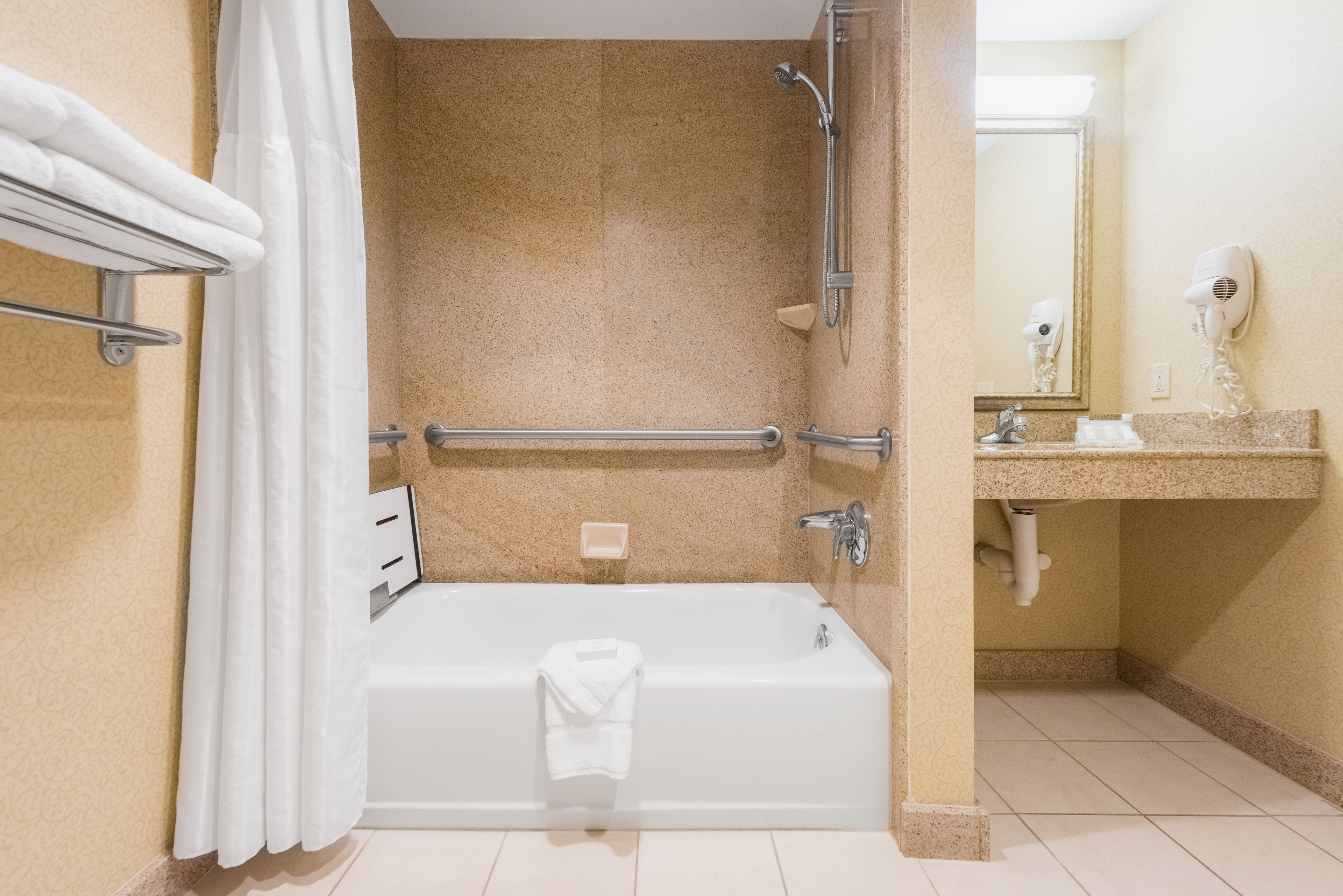 A bathroom with a bathtub, shower, and a vanity with a mirror.