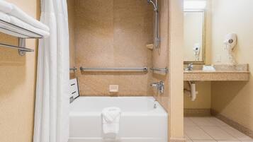 A bathroom with a bathtub, shower, and a vanity with a mirror.