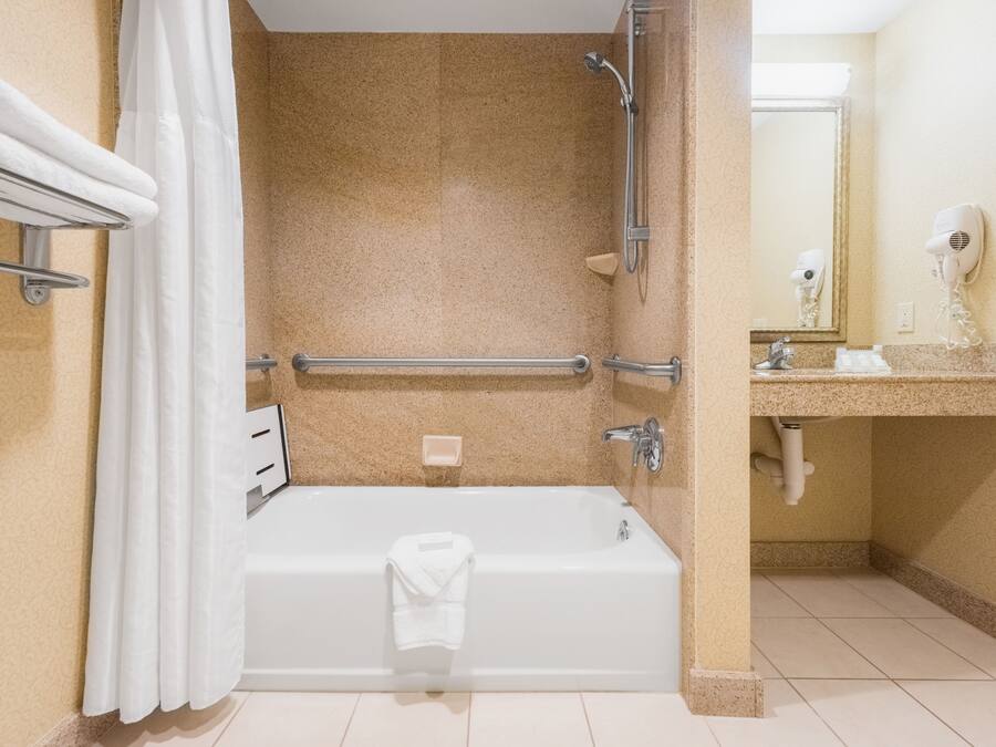 A bathroom with a bathtub, shower, and a vanity with a mirror.
