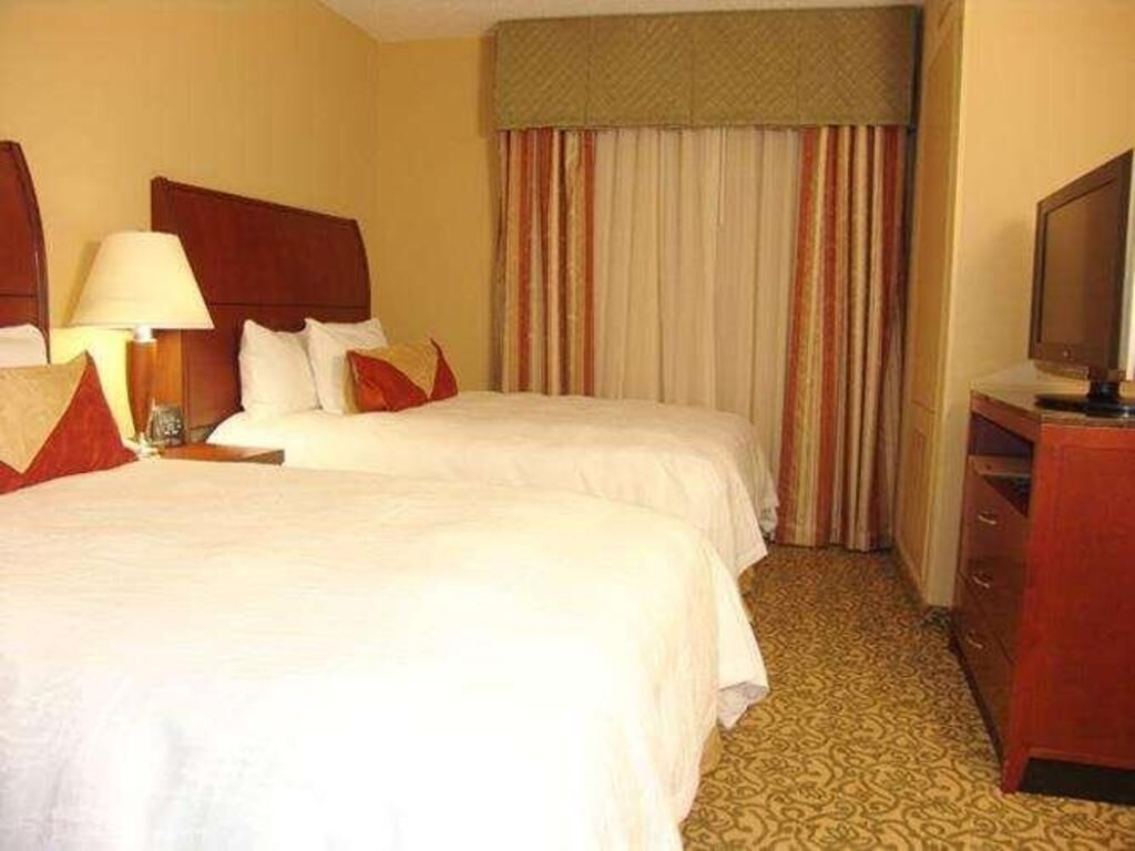 Escritorio, cortinas opacas, tabla de planchar con plancha