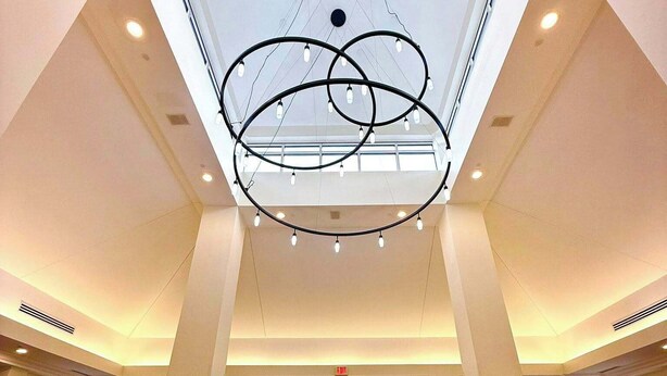 A spacious lobby with a high ceiling, a central chandelier, and a glass entrance.