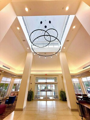 A spacious lobby with a high ceiling, a central chandelier, and a glass entrance.
