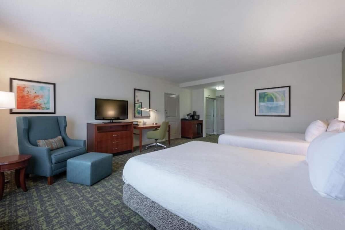 A hotel room with a bed, a desk with a computer, a chair, a television, and artwork on the walls.