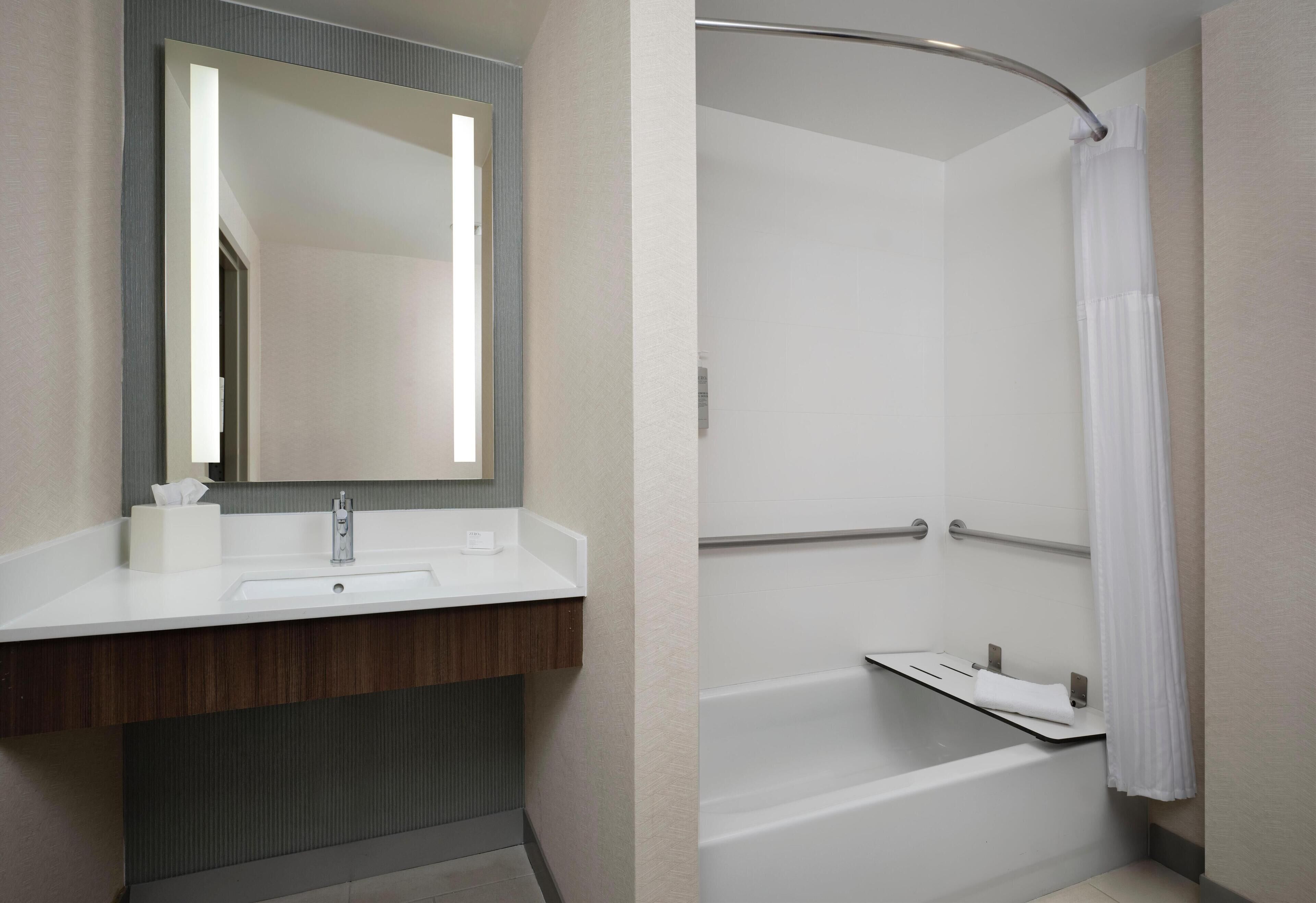 Un baño moderno con lavamanos blanco, espejo y zona de ducha.