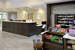 Zona de recepción de un hotel con mostrador, tienda y exhibición de bebidas.