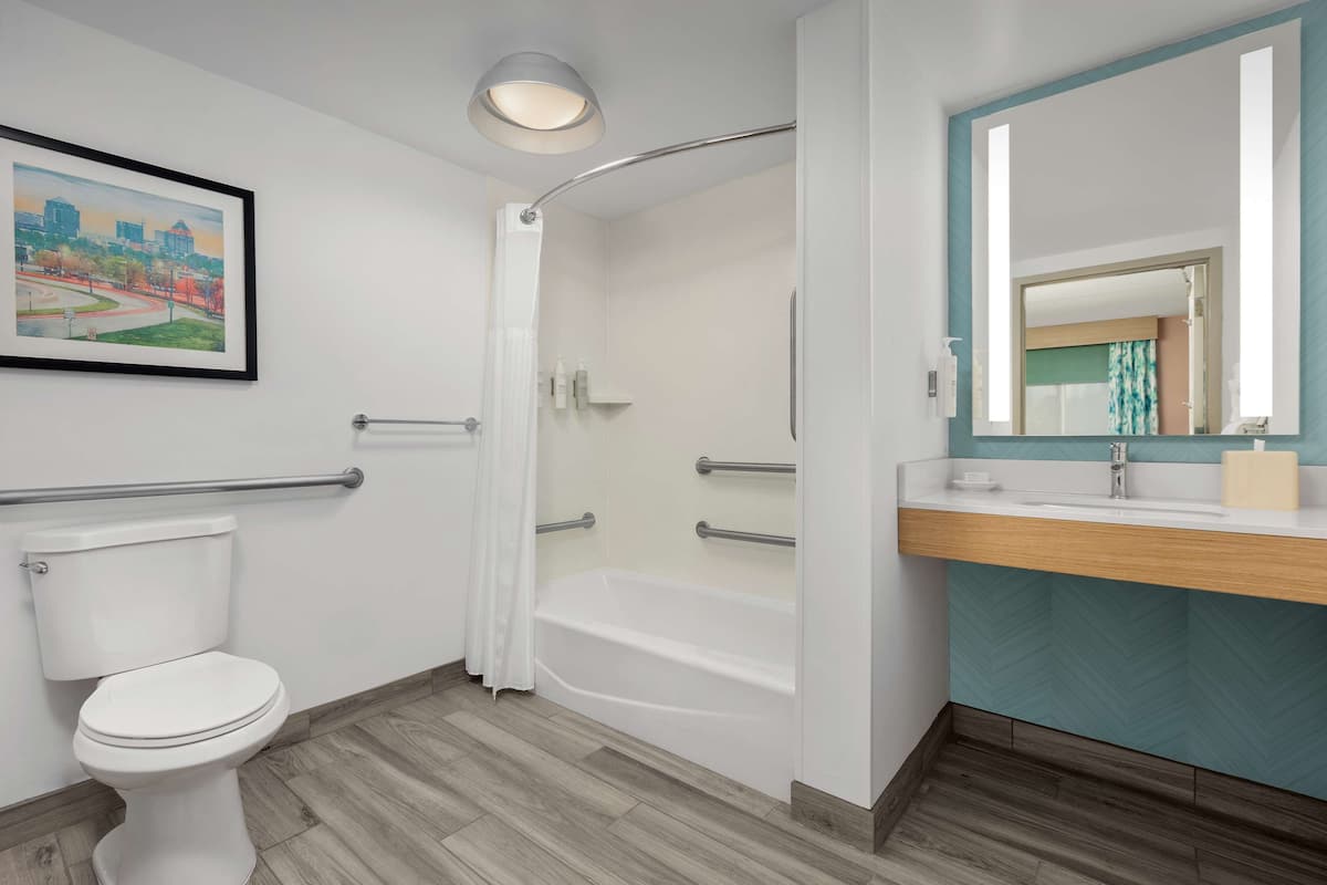A modern bathroom with a toilet, shower, and sink.