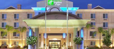 Een Holiday Inn Express & Suites hotel met een opvallende ingang, een overdekte doorgang en een goed verlichte gevel.