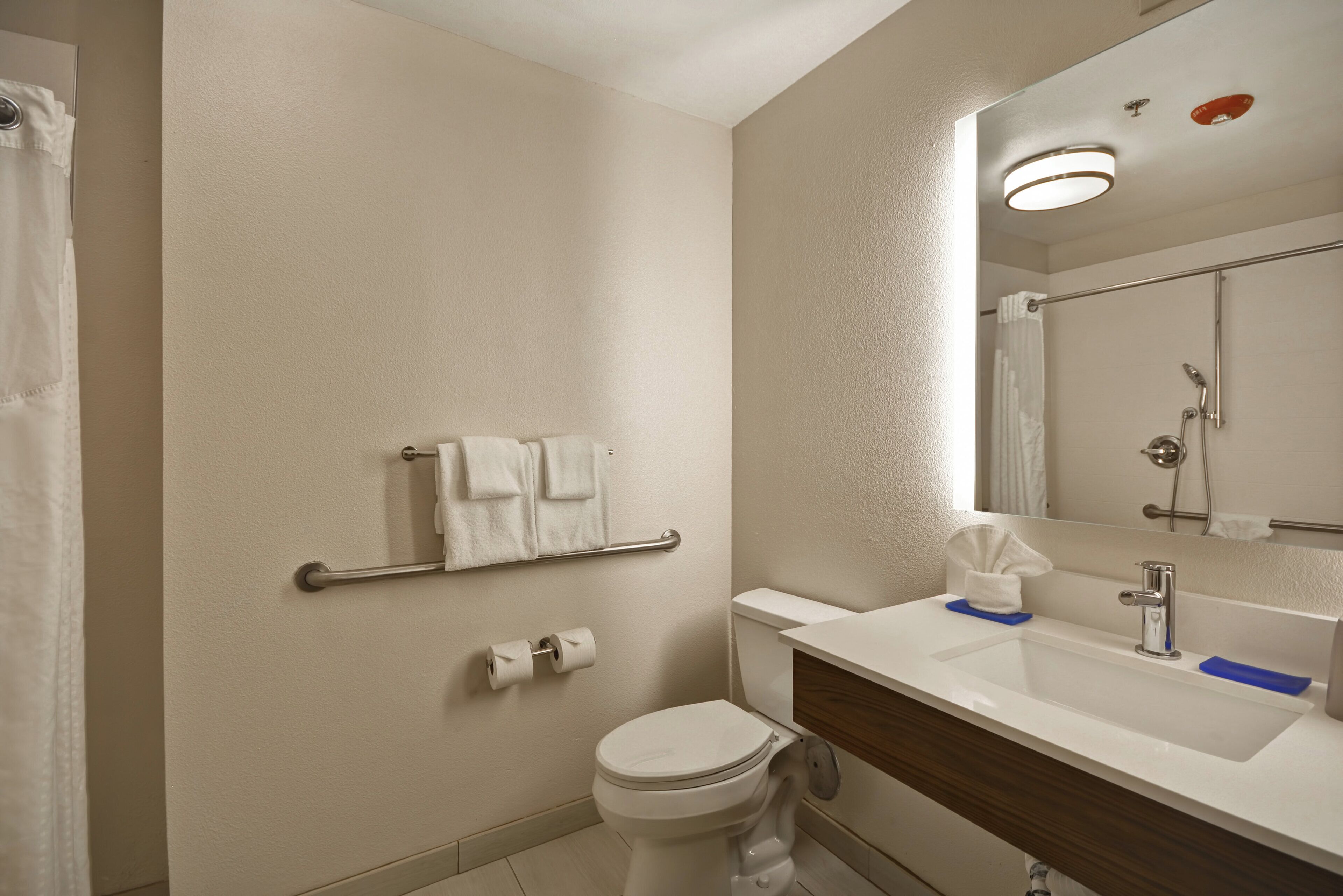 Een badkamer met toilet, wastafel, handdoekhouder en douche.