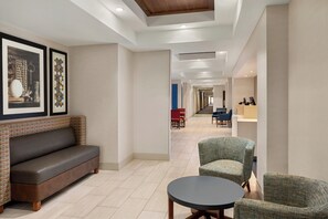 A hotel lobby with a sofa, chairs, a round table, and framed artwork on the wall. - Holiday Inn Express & Suites McAlester by IHG (McAlester)
