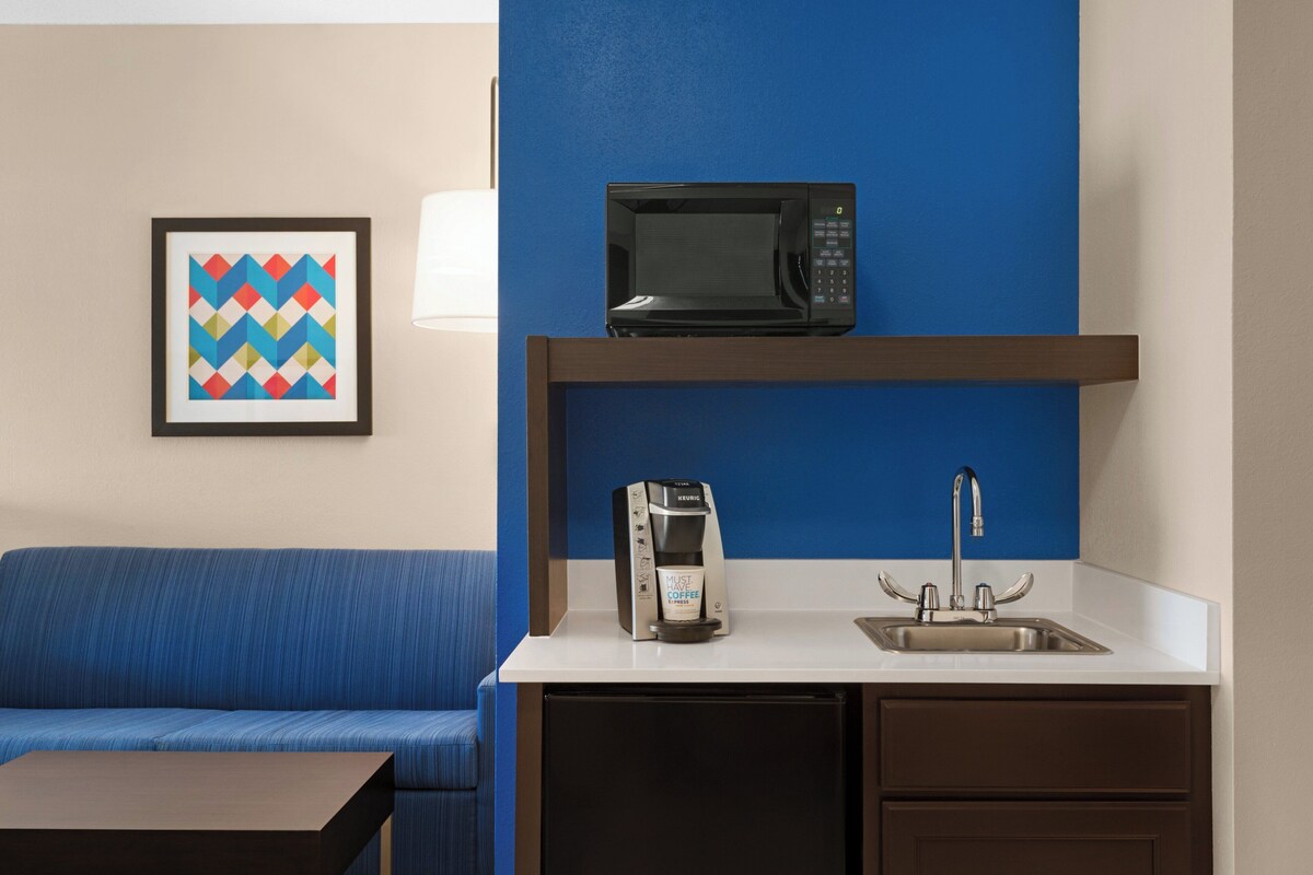 A kitchenette with a microwave, coffee maker, and sink.
