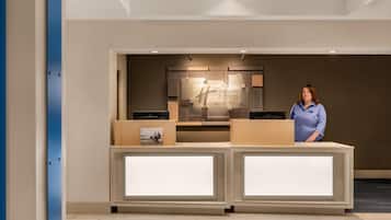 A reception desk with a sign reading "Holiday Inn Express Suites" and a person standing behind it.