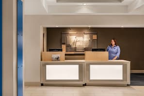 A reception desk with a sign reading "Holiday Inn Express Suites" and a person standing behind it.