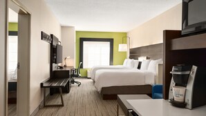 Una habitación de hotel con una cama, un escritorio, una cafetera y un televisor.