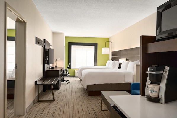 A hotel room with a bed, a desk, a coffee maker, and a TV.