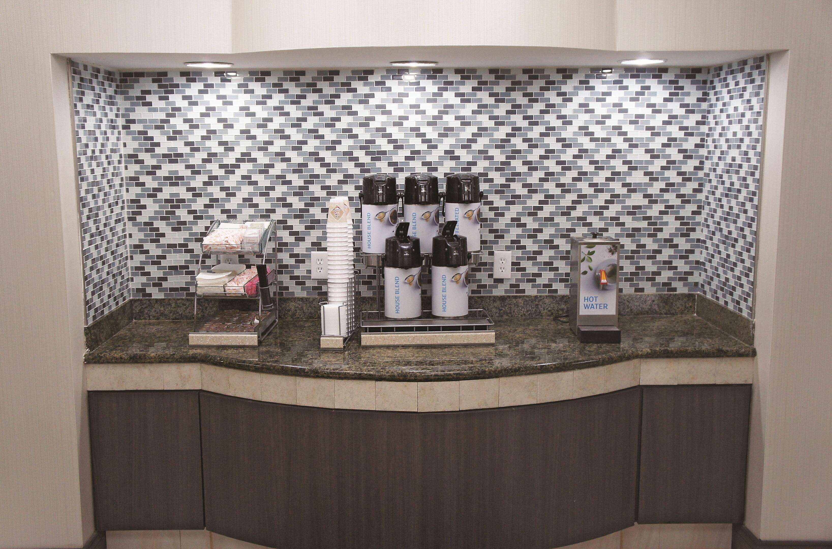 Una estación de café con varios dispensadores de café y un dispensador de agua caliente.