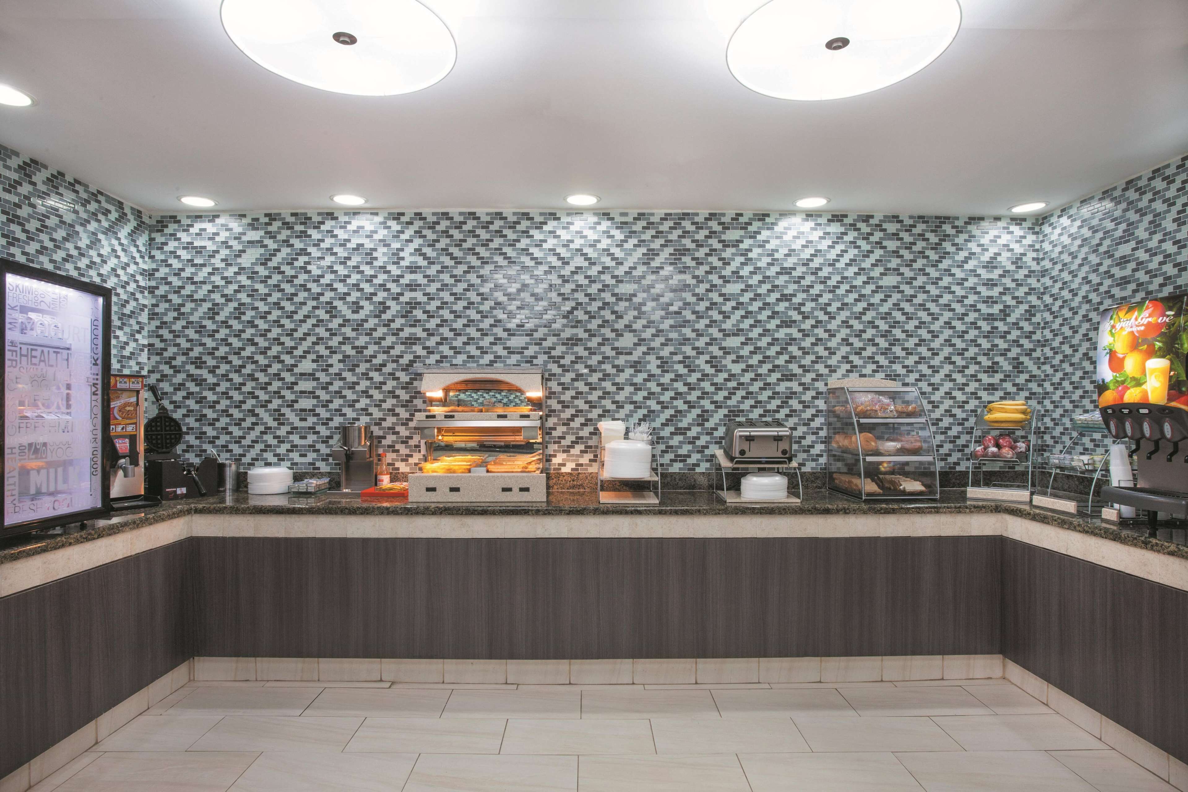 Eine moderne Frühstückstheke mit Mosaikfliesen an der Rückwand, einer Glasvitrine und einer digitalen Menütafel.