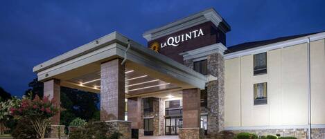 A hotel entrance with a covered walkway, stone pillars, and a sign reading "LA QUINTA".