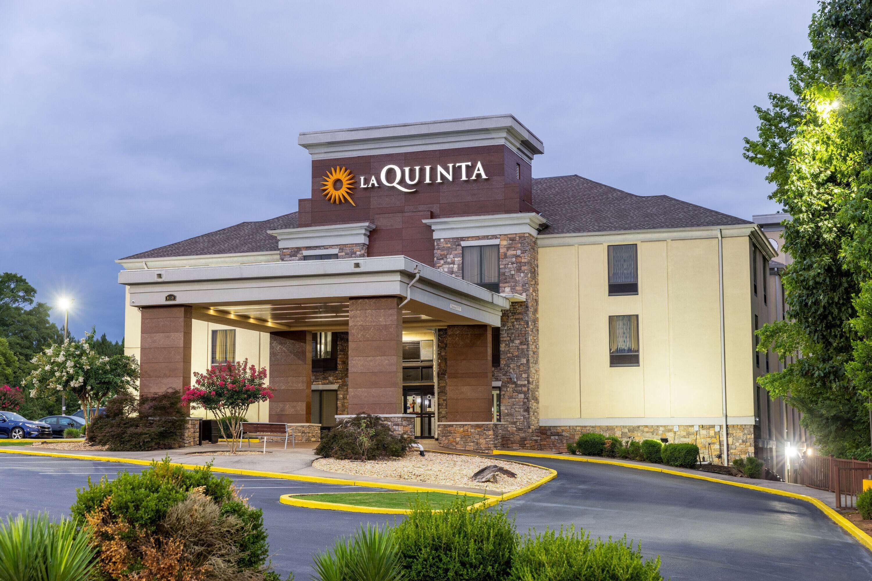 A La Quinta hotel with a prominent entrance, outdoor seating, and a parking lot.
