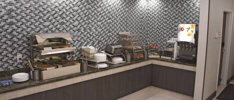 A breakfast bar with a tiled backsplash, a coffee machine, and a refrigerator with fruit magnets.