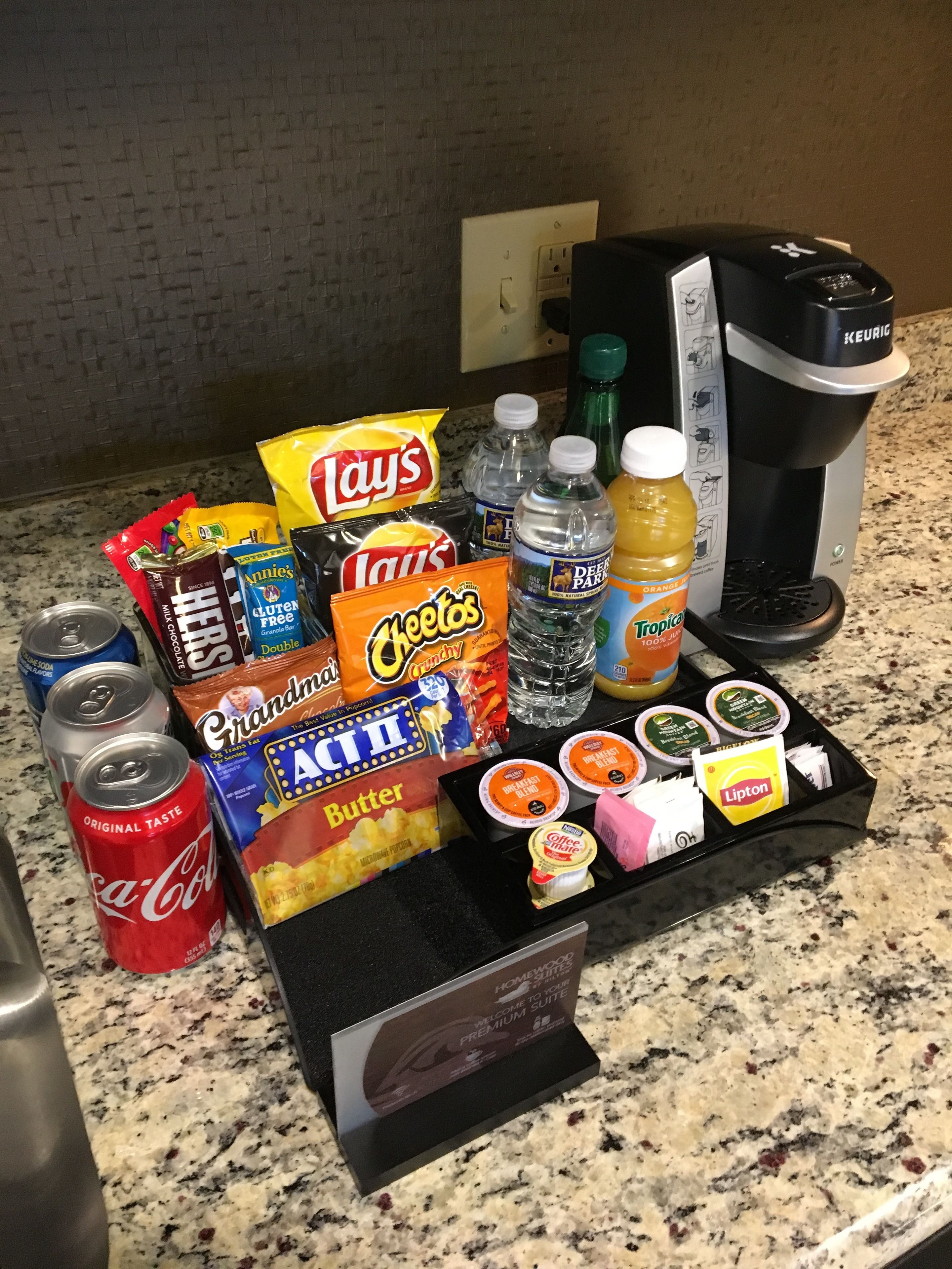 A breakfast tray with snacks, drinks, and coffee on a granite countertop.