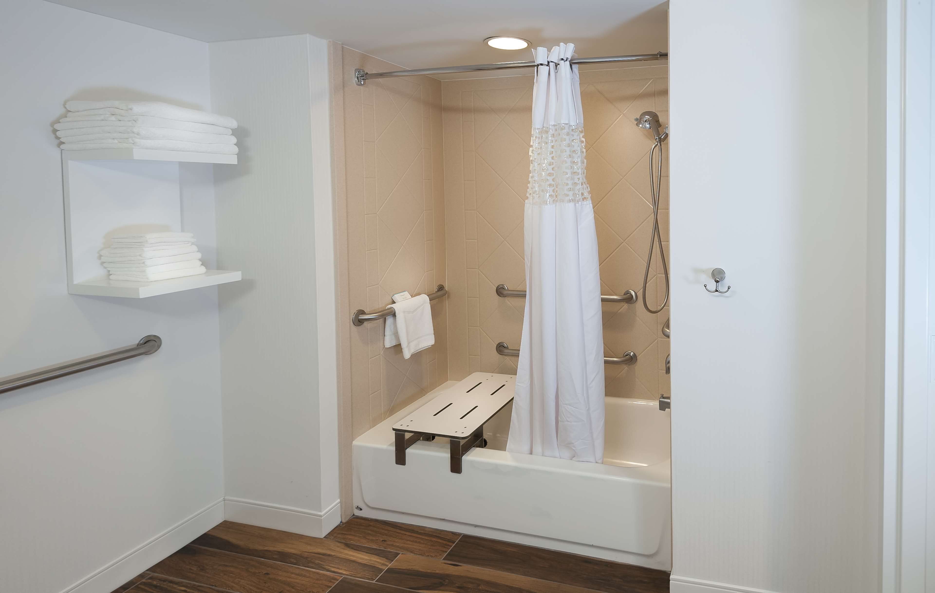 A bathroom with a shower, a bathtub, and a shelf with towels.