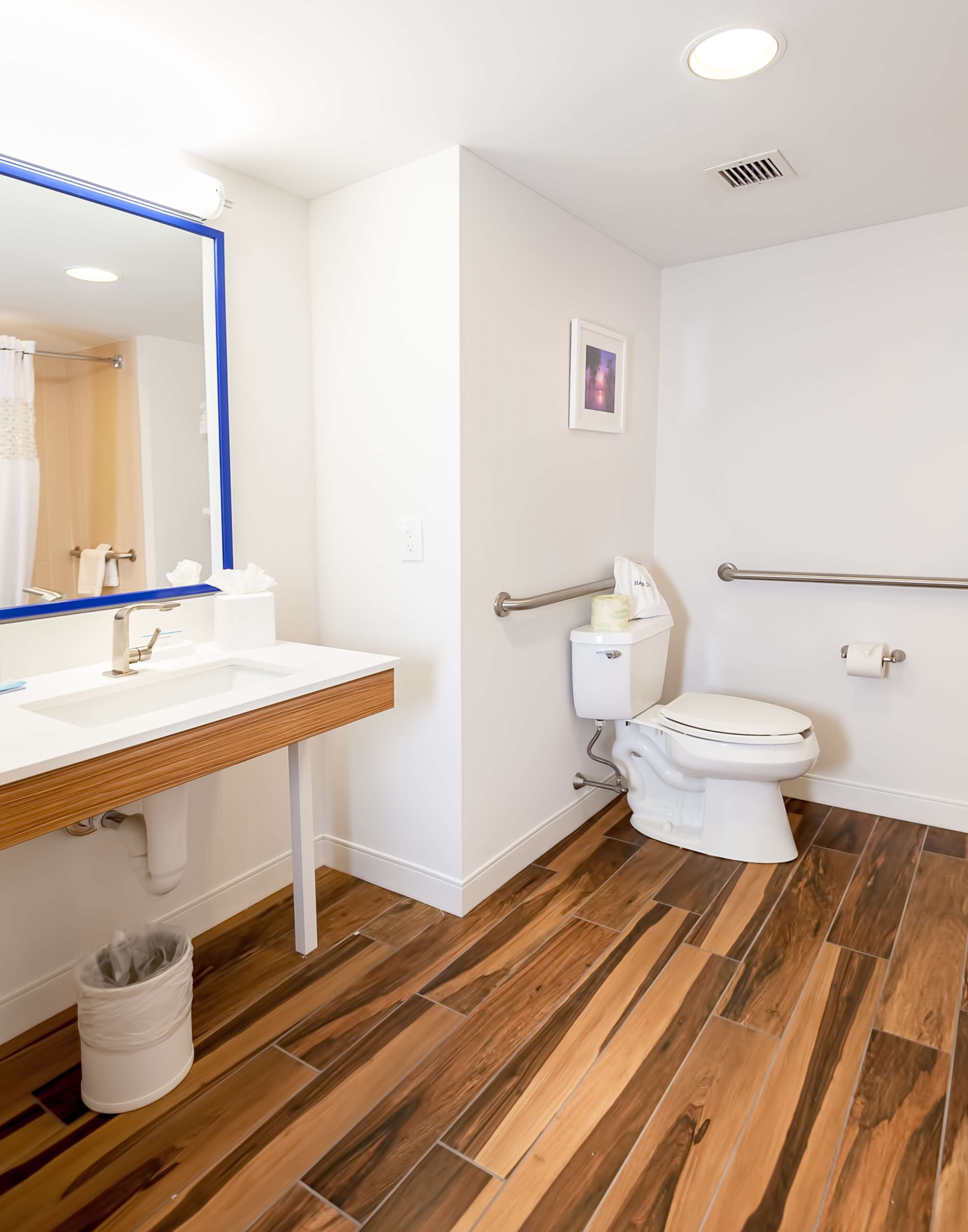Une salle de bain avec un meuble-lavabo en bois, un lavabo blanc et des toilettes.