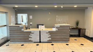 A reception desk with a modern design, a digital screen, and a potted plant. - La Quinta Inn & Suites by Wyndham Tulare (Tulare)