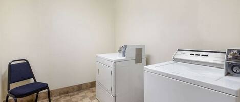 A laundry room with a chair, a front-loading washer, and a stacked washer and dryer.