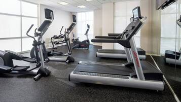 A gym with treadmills, ellipticals, and a mirrored wall.