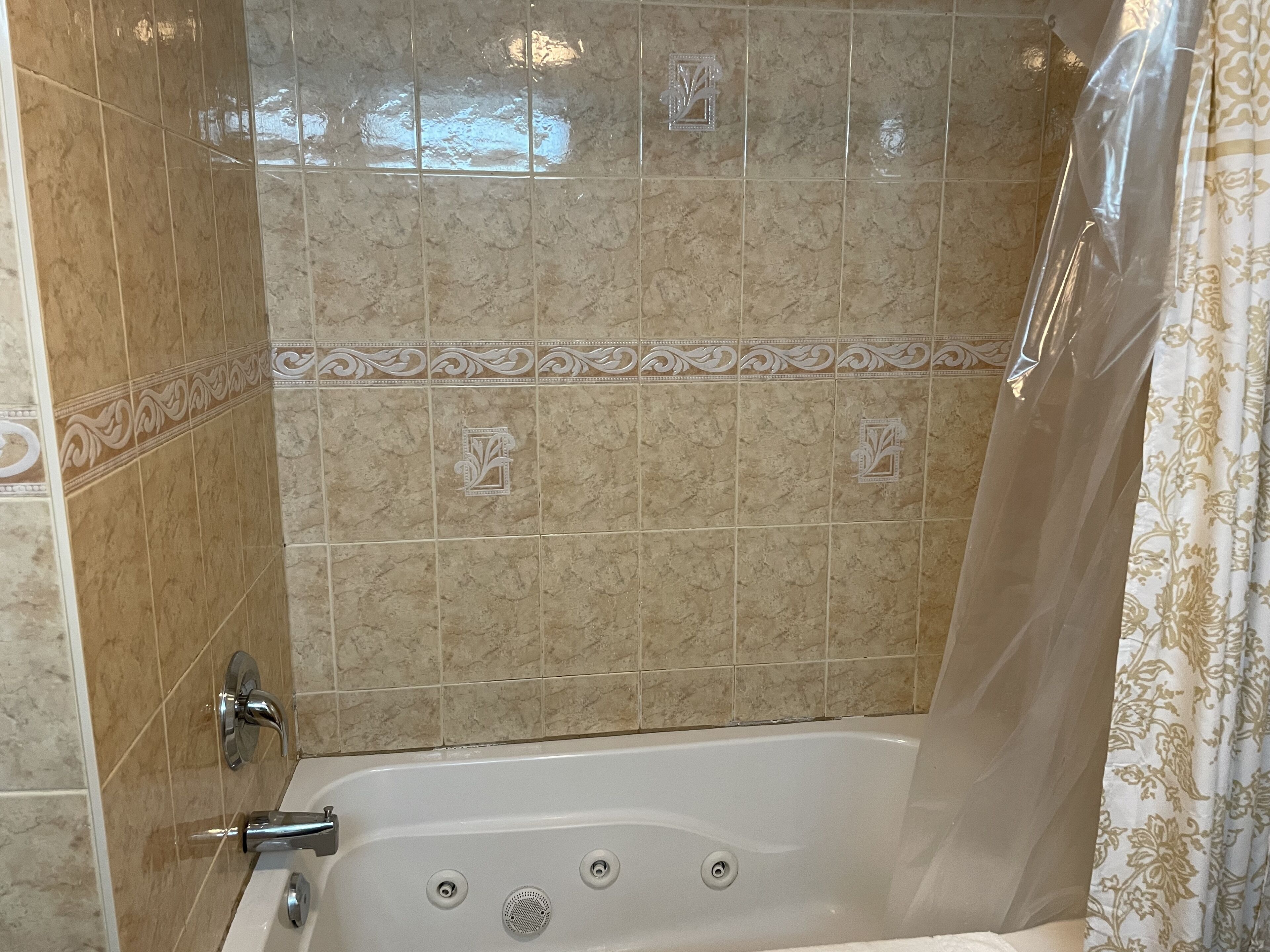 A bathroom with a bathtub, tiled walls, and a shower curtain.