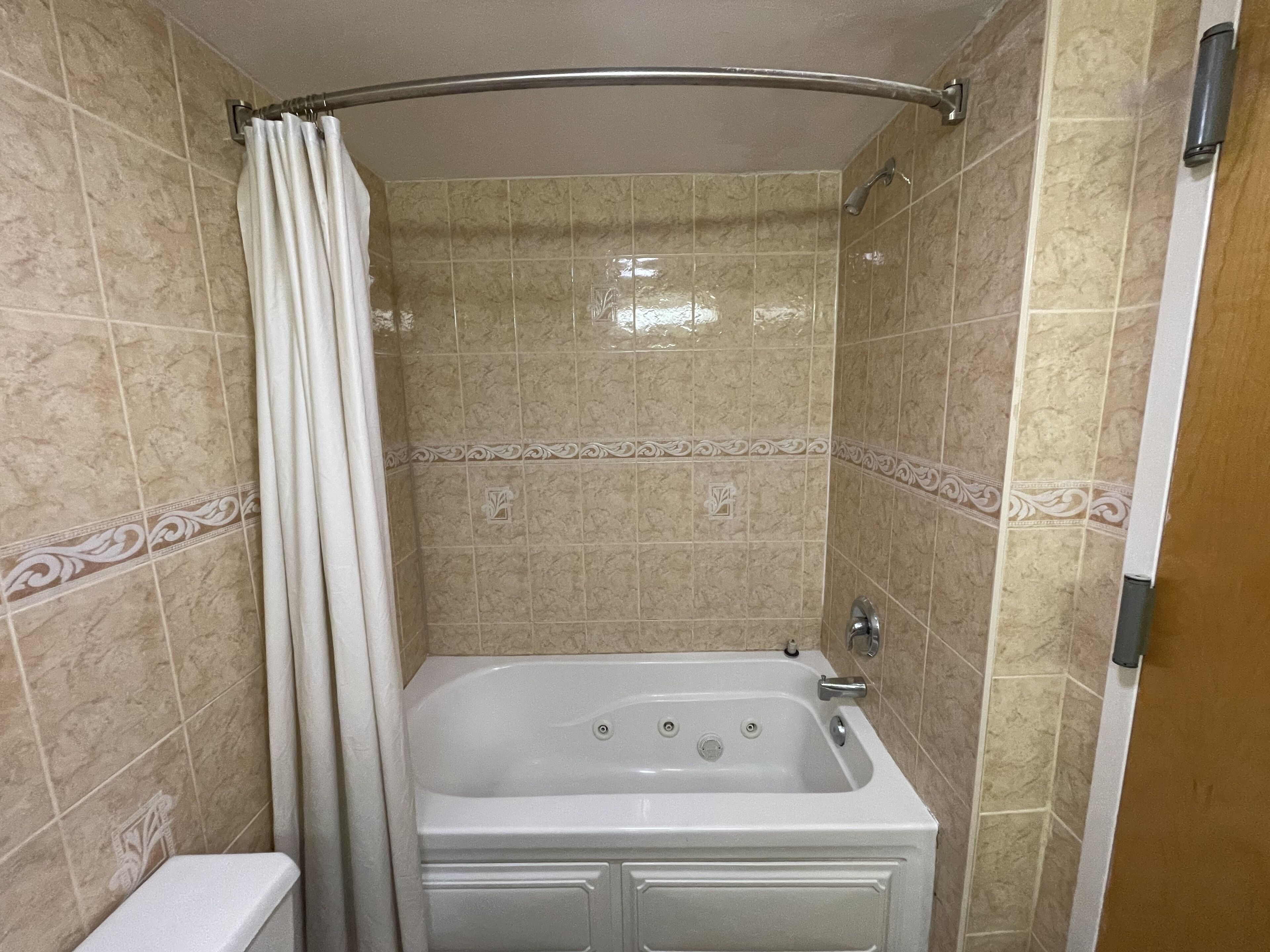 A bathroom with a bathtub, a shower curtain, and tiled walls.