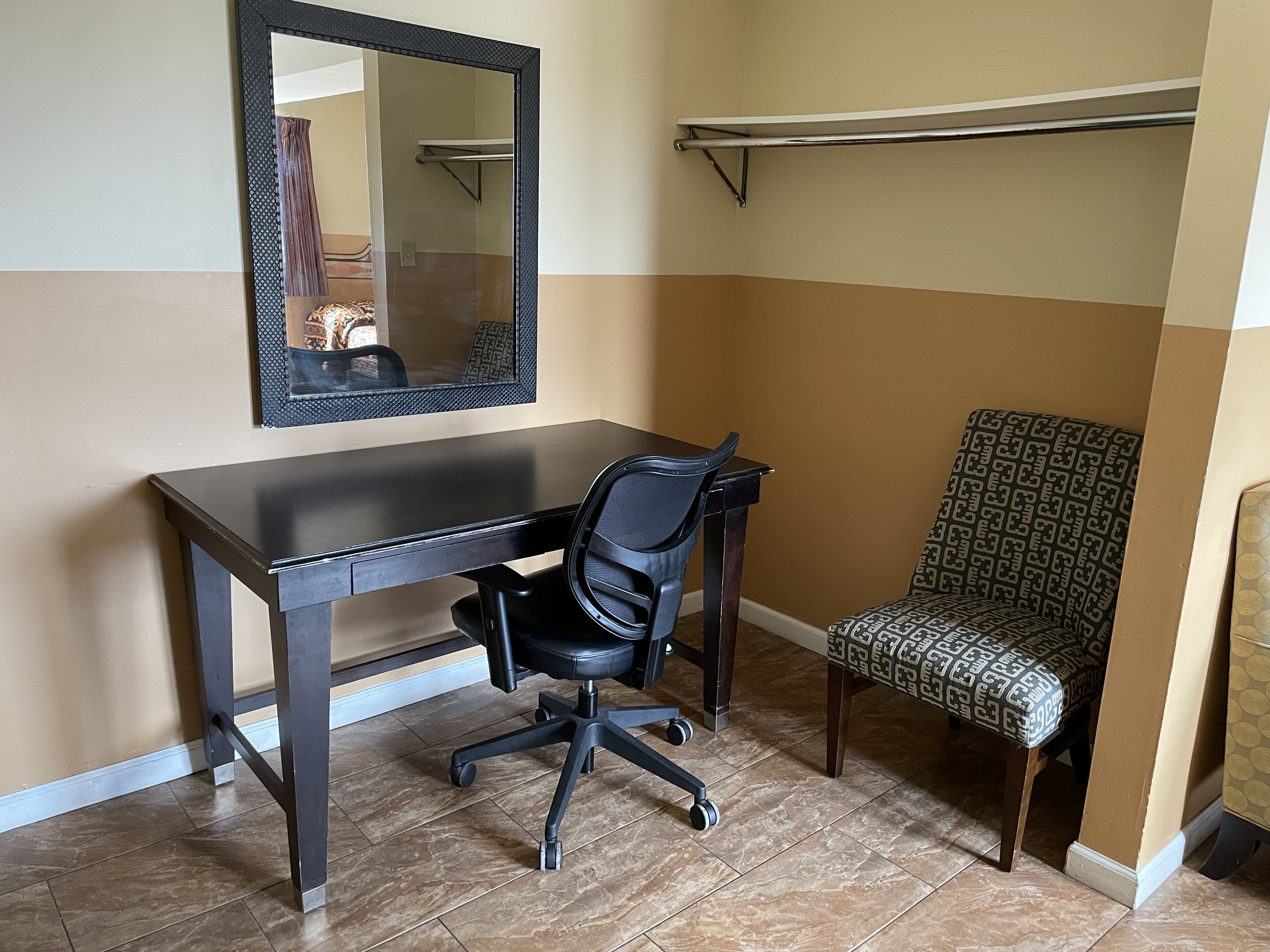 A small office space with a desk, chair, and a mirror on the wall.
