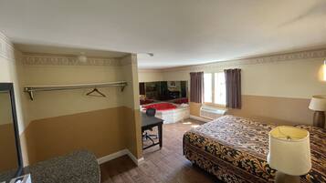 Habitación de hotel con cama, escritorio, silla, perchero y baño con bañera.