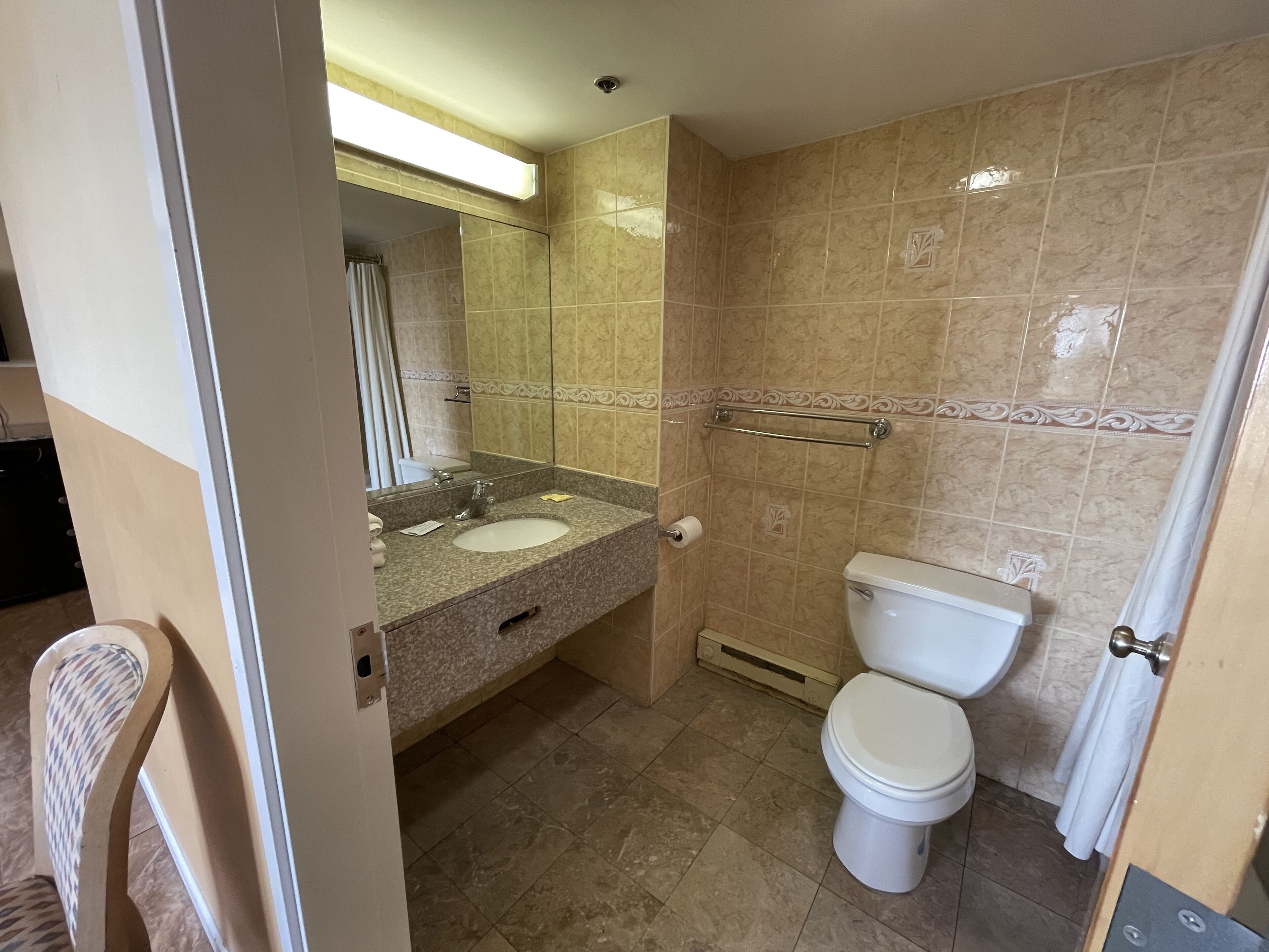 Une salle de bain équipée d’un lavabo, d’un miroir, de toilettes et d’une douche.