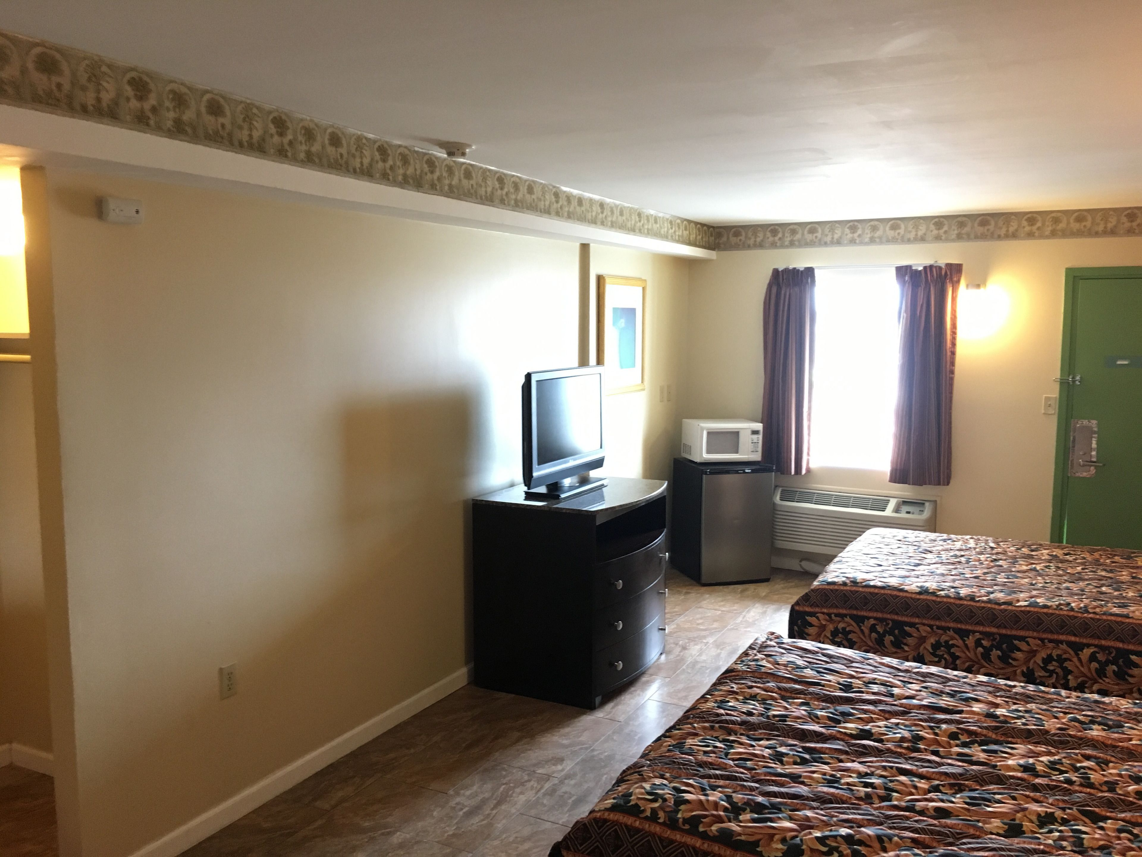 A hotel room with a bed, a TV, a microwave, and a dresser.
