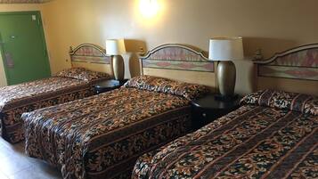 Een hotelkamer met drie bedden, elk voorzien van beddengoed met een patroon en nachtlampjes.