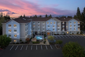 A multi-story hotel with a swimming pool, parking lot, and a view of the sunset. - TownePlace Suites by Marriott Sacramento Cal Expo (Sacramento)
