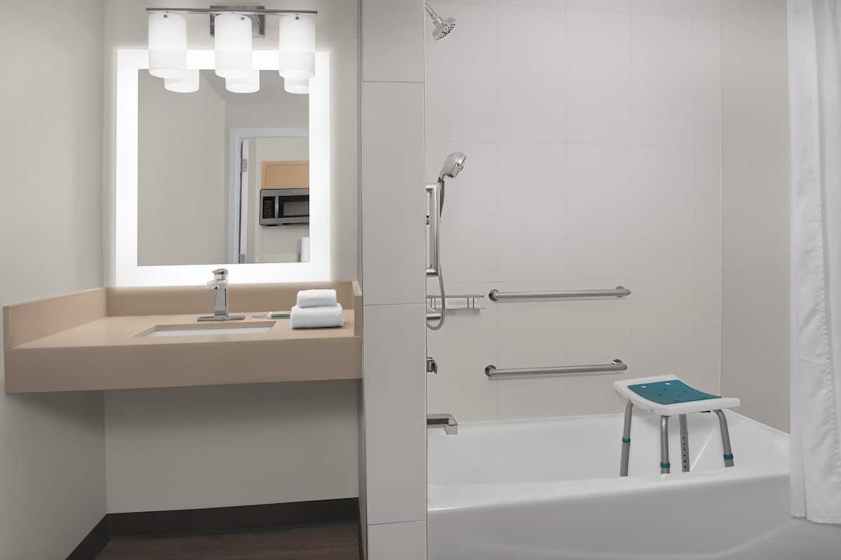 Un baño moderno con lavamanos, espejo y ducha.