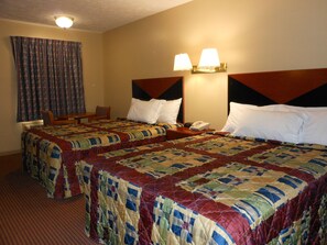 Une chambre d’hôtel avec deux lits, un bureau, une chaise et un téléphone.
