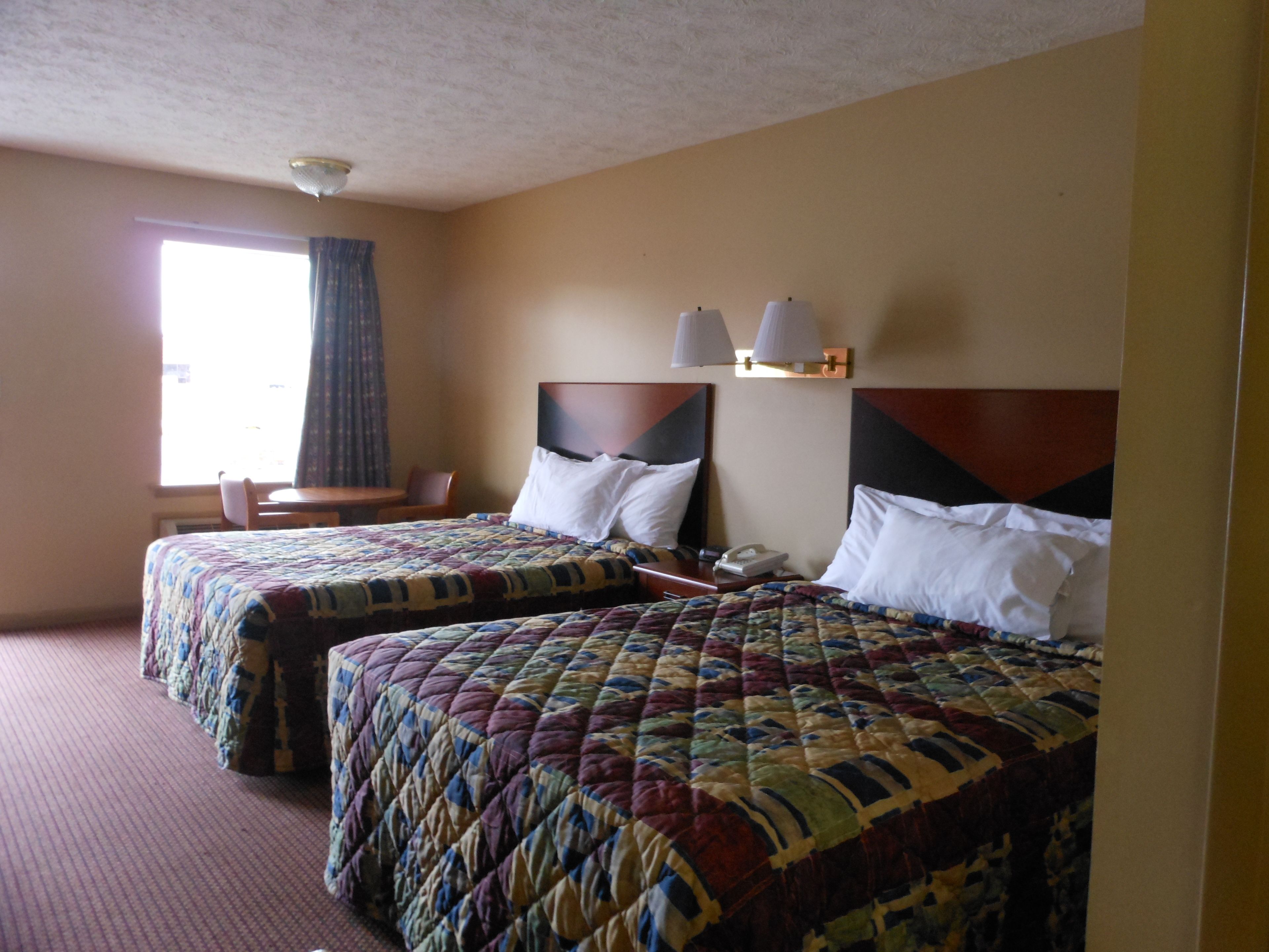 A hotel room with two beds, a desk, and a chair.
