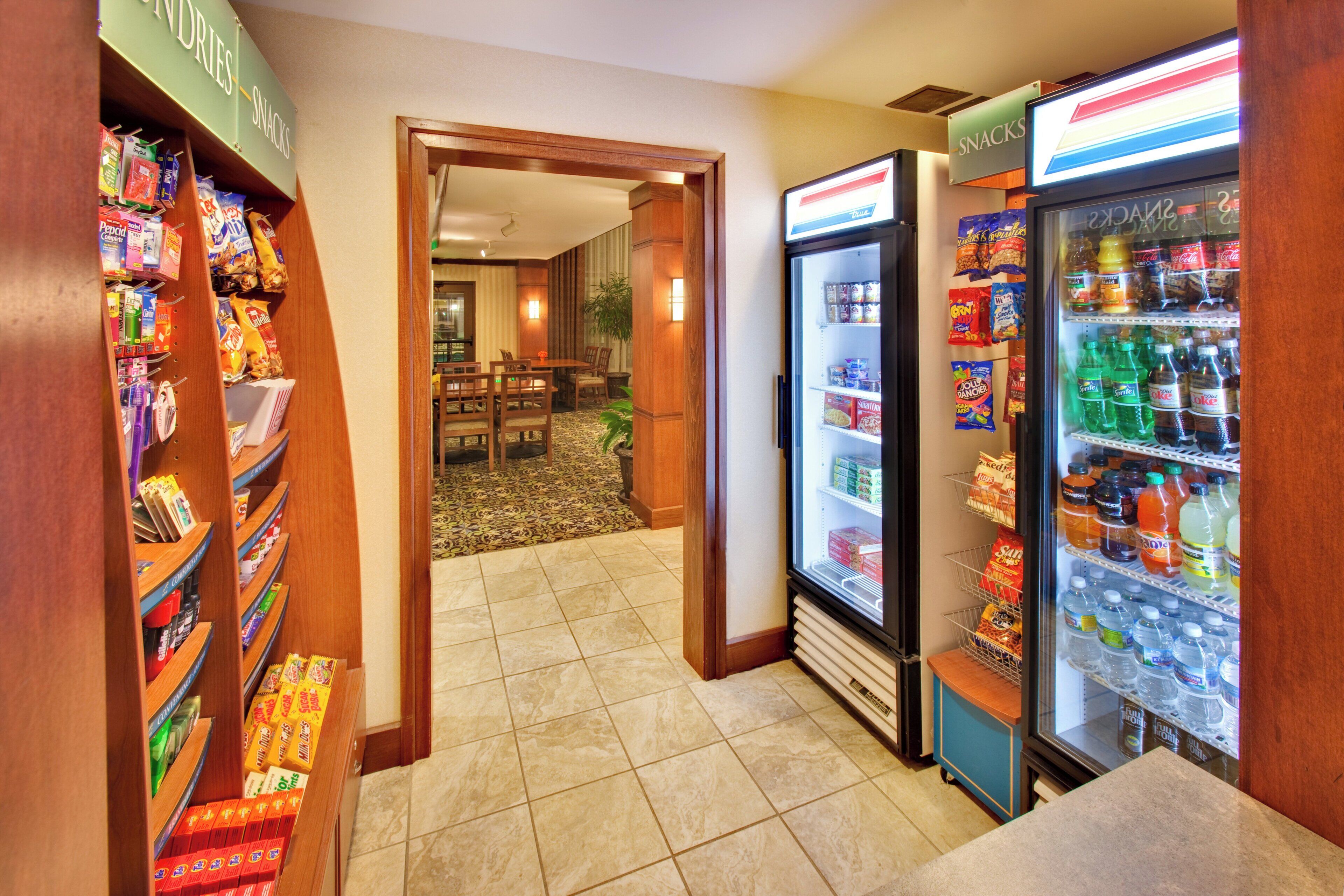Un bar de aperitivos dentro de un hotel, con estantes llenos de diversos bocadillos y un refrigerador con bebidas.
