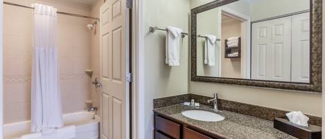 A bathroom with a bathtub, a sink, a mirror, and a towel rack.