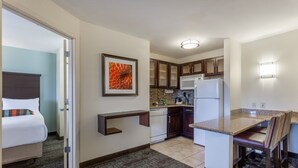 A compact hotel room with a bed, a small kitchenette, a dining area, and a bathroom. - Staybridge Suites Davenport by IHG (Davenport)