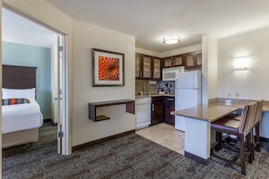 A compact hotel room with a bed, a small kitchenette, a dining area, and a bathroom. - Staybridge Suites Davenport by IHG (Davenport)
