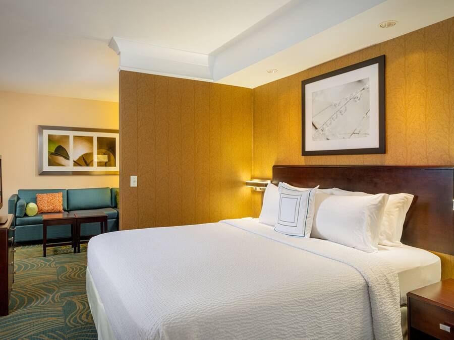A hotel room with a large bed, a sofa, a desk, and a wall-mounted TV.