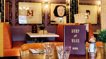 A restaurant interior with a table set for two, featuring a menu titled "RUMP AND WADE DRINKS".