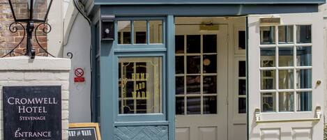 A hotel entrance with a sign reading "CROMWELL HOTEL" and a chalkboard sign listing specials.