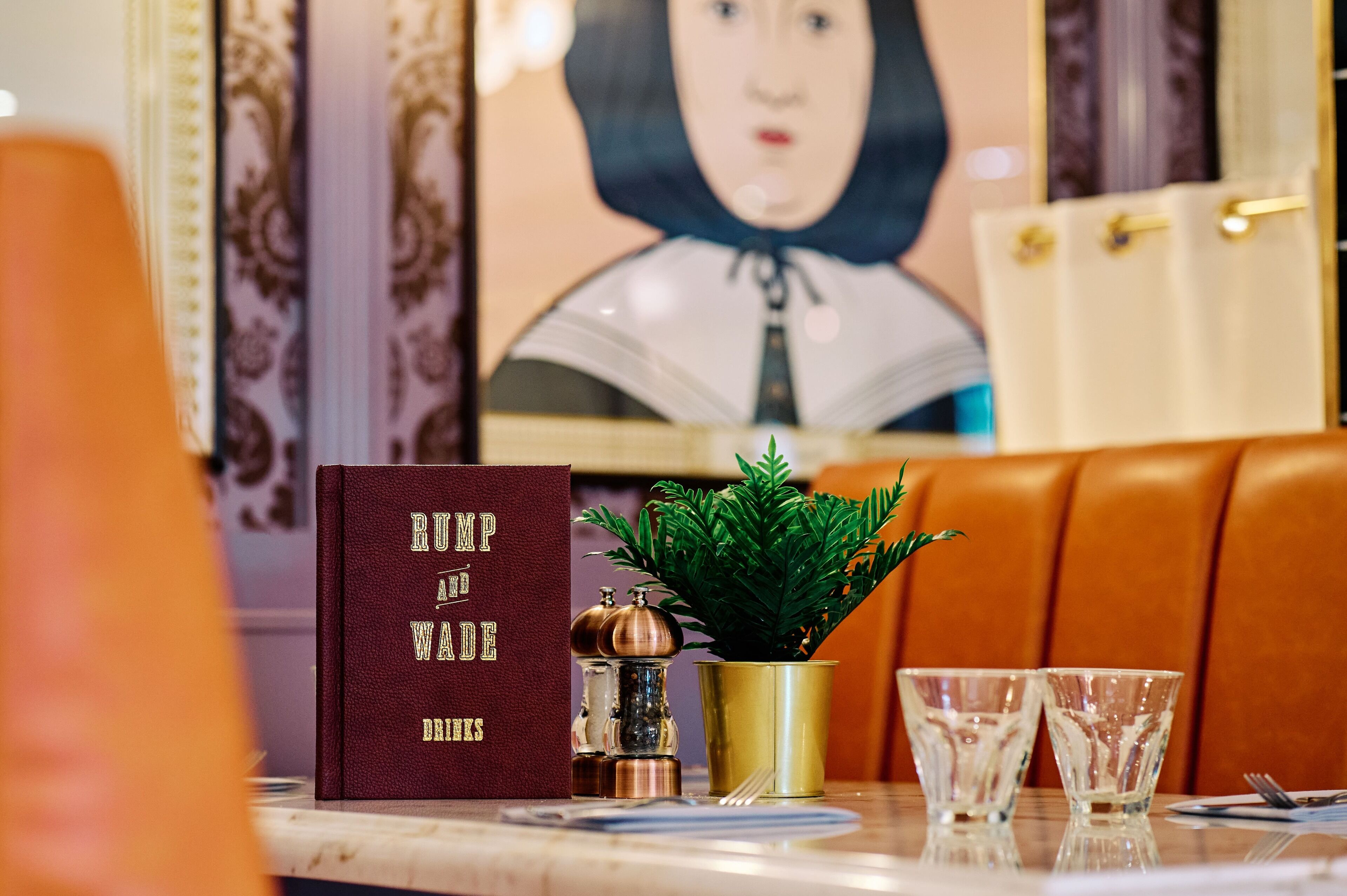 A table with a book titled 'Rump and Wade', a small potted plant, and two glasses.